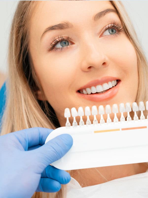 A woman is smiling while holding a toothbrush.